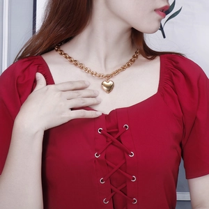 Close-up of a large gold heart pendant necklace on model with chunky link chain
