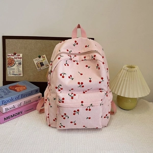Detail of pink corduroy backpack with red cherry pattern and front zipper pocket