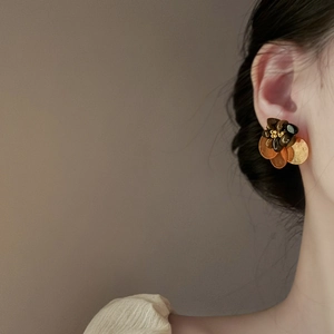 Macro shot of vintage gold shell and tiger eye stone flower earrings on model