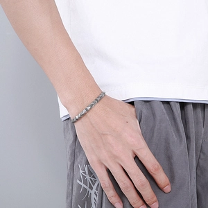 Detail of silver titanium steel cuff bracelet with arrow pattern on male model wrist