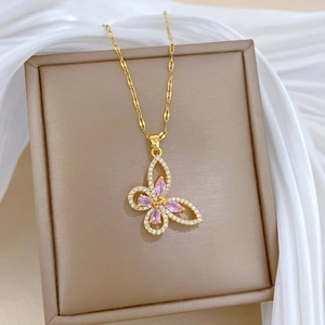 Macro detail of gold butterfly pendant with pink marquise stones and zircon accents