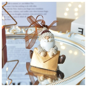 Close-up of Santa Claus resin ornament in a gold envelope with brown ribbon