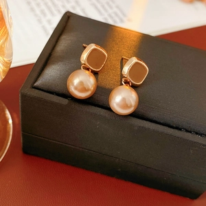 Dettaglio macro di orecchini vintage dorati con smalto marrone e perle champagne