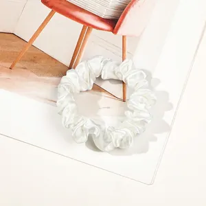 Detailed view of a white satin scrunchie with high-gloss silk texture and elegant folds
