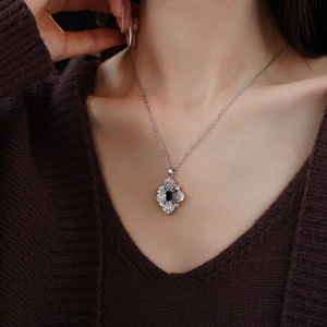 Close-up of elegant silver necklace with black diamond-shaped stone pendant on neck