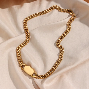 Golden chunky curb chain necklace with oval metal clasp on beige silk fabric background