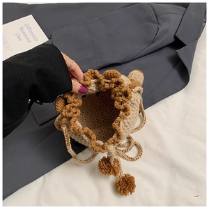 Macro view of beige handmade crochet drawstring bag with brown scalloped edges and tassels