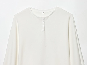 Detail of white Henley neck long sleeve top with cotton knit texture and buttoned neckline