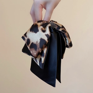 Detail of leopard print fabric bow hair claw clip with sparkling rhinestone center
