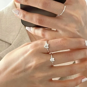 Detailed view of silver heart and flower rings styled on fingers for a trendy look