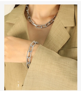 Detail of silver paperclip chain necklace and bracelet set worn with a blazer