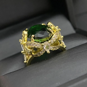 Macro shot of large oval green gemstone ring with gold floral setting and zircons