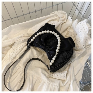 Detailed top view of black handbag with large bow and elegant pearl handle accessory
