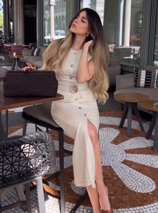 Dettaglio dell'abito midi in lino beige con bottoni e pochette intrecciata a mano