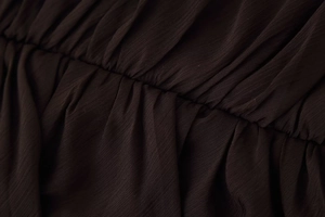 Close-up detail of dark brown pleated fabric texture and professional stitching finish