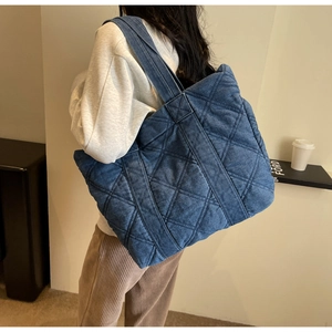 Détail du grand sac cabas en denim matelassé bleu avec larges bandoulières et haute capacité
