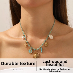 Detailed view of woven necklace with star, sun, moon and sea turtle pendants