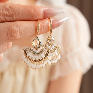 Détail de boucles d'oreilles vintage en éventail avec zircons champagne et pompons de perles