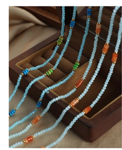 Détail d'un collier de perles bohème avec turquoise et pierres colorées sur bois