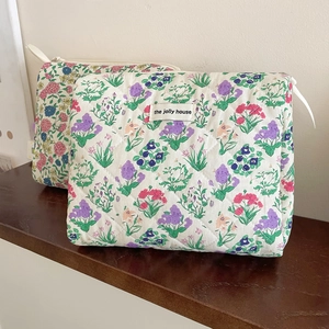 Detail of floral quilted cotton makeup bag with white zipper and branded woven label