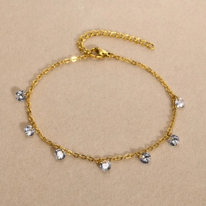 Detail of gold titanium anklet with 7 round cubic zirconia charms and lobster clasp
