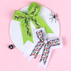 Close-up of Halloween bow hair clips with spider and pumpkin prints on a pink background