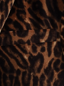 Close-up of leopard print velvet fabric showing the lapel and stitching details of the suit