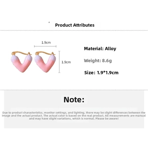Detail view of pink heart earrings with white enamel glaze and golden hooks