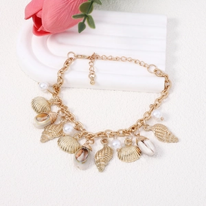 Detail of bohemian gold bracelet featuring seashell, conch pendants and white pearls