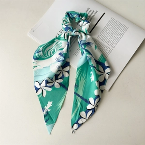 Detailed view of silk-like scrunchie with long streamers and tropical leaf floral prints