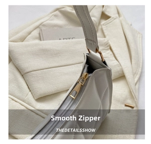 Detail of quilted leather underarm bag with gold zipper and smooth texture