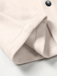 Detailed close-up of beige wool jacket cuff with black button and premium stitching