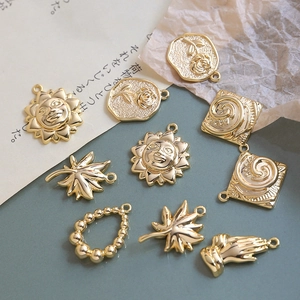 Close-up of vintage gold-plated pendants including sun, maple leaf, and rose for DIY jewelry