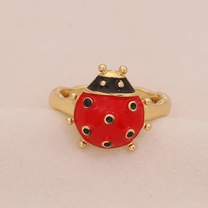 Detail of red and black enamel ladybug ring on a beige velvet background
