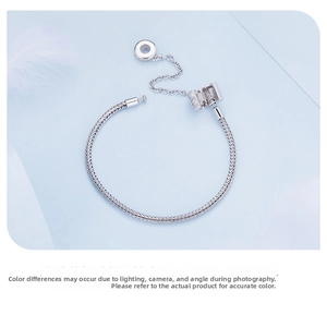 Close-up of silver snake chain bracelet featuring sparkling zircon clasp and safety chain