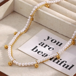 Détail du collier double couche avec perles blanches et clochettes dorées dans son coffret