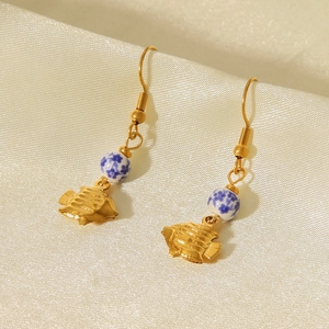 Détail des boucles d'oreilles poisson tropical avec pendentifs dorés et perles en céramique