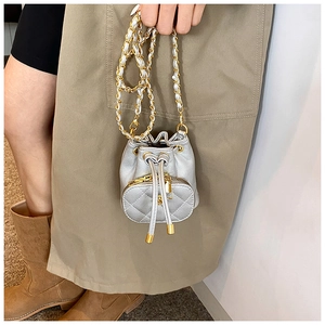 Silver quilted mini bucket bag with leather chain strap shown with a trench coat