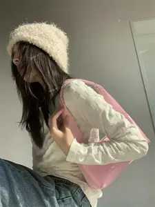 Pink glossy hobo shoulder bag styled with a white waffle knit top and fleece beanie