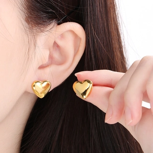 Close-up of elegant gold heart-shaped stud earrings worn by a model for a luxury look