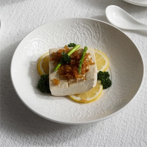 White ceramic dinner plate with embossed floral patterns for elegant table settings