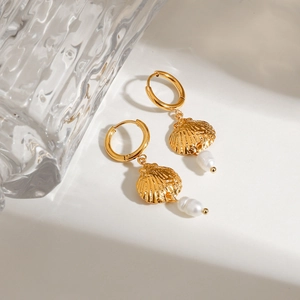 Detail of gold seashell earrings featuring a baroque pearl drop on a minimalist background