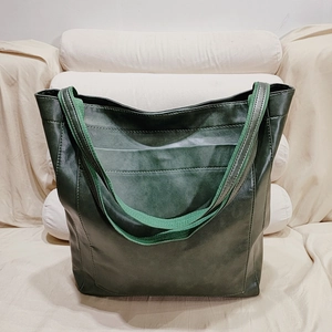 Gros plan détaillé d'un grand sac fourre-tout vert en similicuir sur un canapé beige