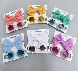 Close-up of children's daisy sunglasses and bow headband sets in six candy colors