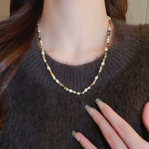 Detailed macro view of freshwater pearls and brown agate beads on a gold necklace