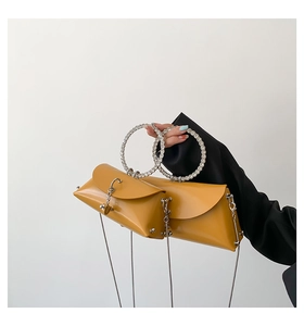 Close-up of mustard yellow handbag with sparkling rhinestone ring handle and metal chain