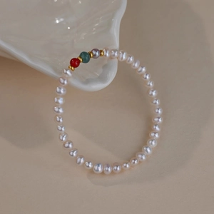 Macro shot of freshwater pearl bracelet with colorful stone beads on ceramic shell tray