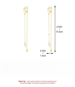 Detailed view of long tassel earrings with white flower elements and pearl accents