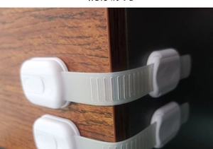 Close-up van verstelbaar wit kinderslot gemonteerd op de hoek van een houten kast