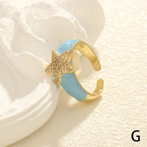 Close-up of golden adjustable star ring featuring blue enamel and sparkling zircon accents